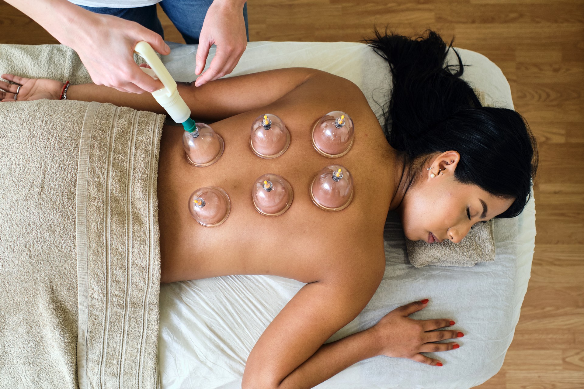 Adult masseuse giving cupping massage to young ecuadorian girl.